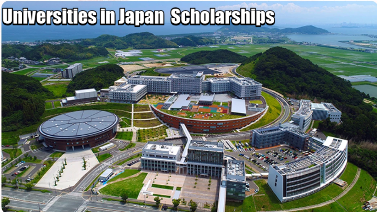 Universities in Japan Aerial view of a large modern university campus in Japan surrounded by green hills, farmlands, and coastal scenery, with buildings arranged in circular and rectangular layouts.